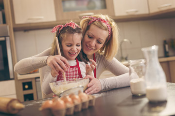 Mother teaching daughter to knead dough
