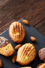 Freshly baked almond cookies on stone board over wooden background, top view, selective focus.
