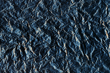 Blue perforated rough surface with cracks and golden inclusions. Ragged stone. Dark background
