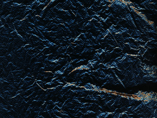 Dark blue perforated rough surface with cracks and golden inclusions. Ragged stone. Dark background