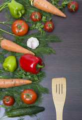 Vegetables concept on a wooden background with a wooden spatula. Carrots with green and red pepper on the table. Fresh vegetables on a brown wooden background.
