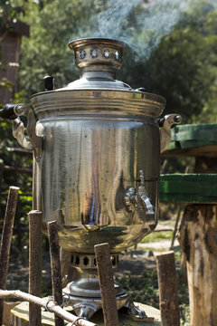 The samovar stands on a stump in the garden.