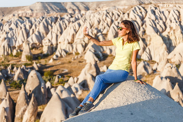 smiling woman in sunglasses taking selfie photo on a smartphone in Cappadocia, Turkey