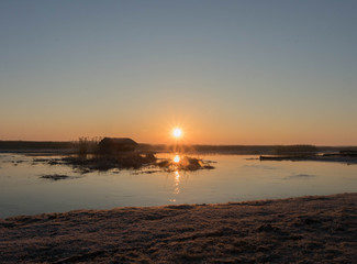 the sun rises red over marshlands and swamps with birds resting on the water and among the reeds