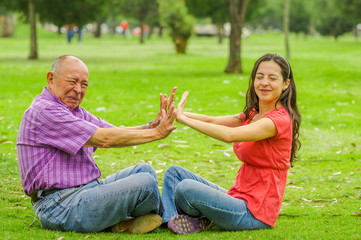 Outdoor view of father and daughter rejecting each other at outdoors sitting in the grass, in the...