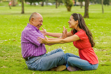 Outdoor view of father rejecting her daughter at outdoors sitting in the ground, in the park