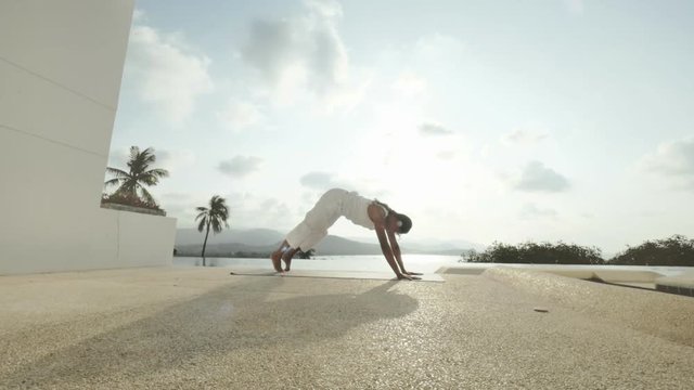 Woman practicing yoga asanas on outdoor terrace with panoramic view