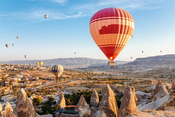 Many Hot air balloons flying over rocky landscape in Goreme city at Cappadocia, Turkey