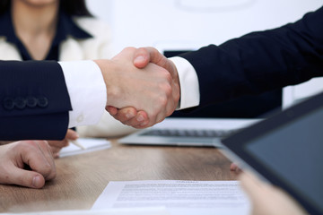 Close up of business people shaking hands at meeting or negotiation in the office. Partners are satisfied because signing contract