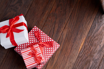 Fototapeta na wymiar Still life with holiday gift in small red color box with ribbon and bow on wooden background, top view, close-up