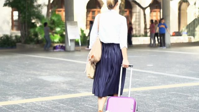 Businesswoman with suitcase walking in city, slow motion 240fps
