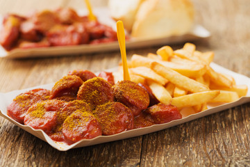 Traditional German currywurst, served with chips on disposable paper tray.