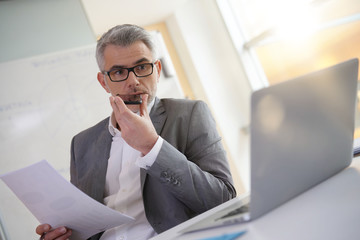 Naklejka premium Businessman in office using smartphone