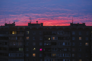 Fototapeta na wymiar The sun sits behind a multi-story building. City sunset