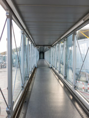 Vertical view of the airport bridge, where passengers connect with the plane. - obrazy, fototapety, plakaty