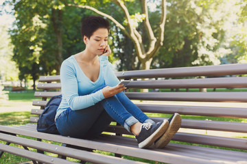 Concentrated woman typing on mobile outdoors