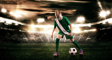 Kid - soccer player. Boy forward in football sportswear on stadium with ball. Sport concept.