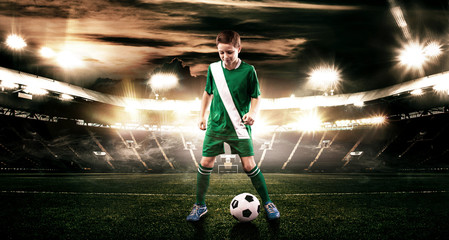 Kid - soccer player. Boy forward in football sportswear on stadium with ball. Sport concept.