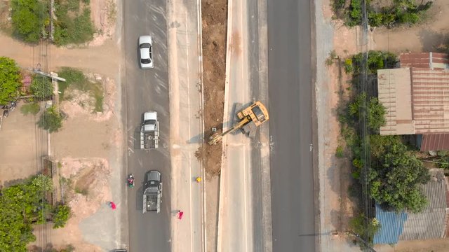 Excavator backhoe filling soil to the construction site road