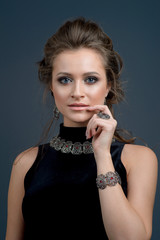 Obraz premium Beautiful woman in a necklace, earrings and ring. Model in jewelry. Studio photo on a dark blue background