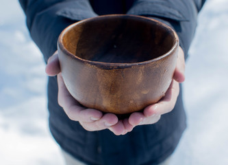 Men hand holding empty wooden bowl