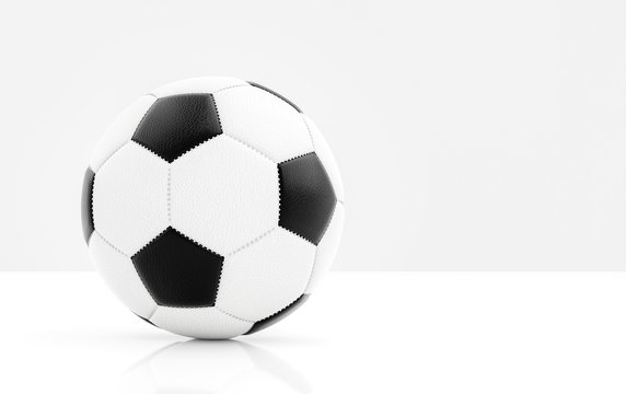 Traditional soccer ball with stitching on white surface with reflection and light grey background and copyspace