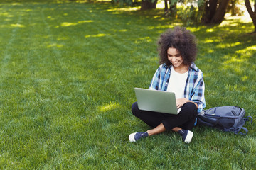 Happy young black woman using laptop in park