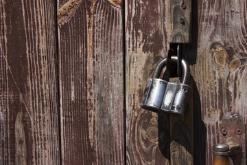 Closed metal lock hanging on the wooden brown old doors. Protection from thieves.