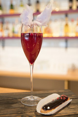 Red cocktail with a chocolate eclair against the bar