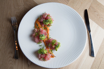 Tuna tartare with green sauce on a white plate