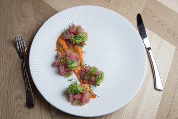 Tuna tartare with green sauce on a white plate