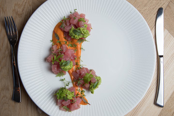 Tuna tartare with green sauce on a white plate
