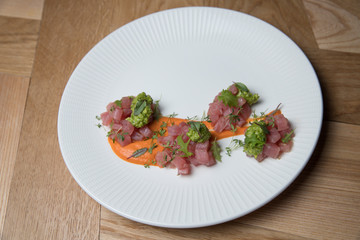 Tuna tartare with green sauce on a white plate