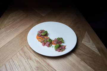 Tuna tartare with green sauce on a white plate