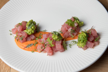 Tuna tartare with green sauce on a white plate