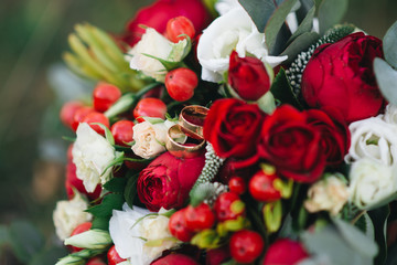 Wedding engagement rings and flowers wedding bouquet background, selective focus, macro