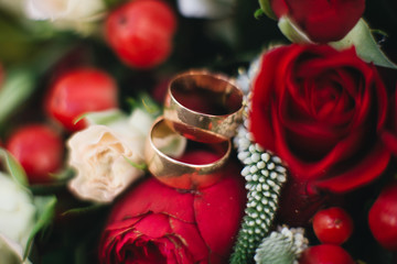 Wedding engagement rings and flowers wedding bouquet background, selective focus, macro