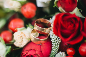 Wedding engagement rings and flowers wedding bouquet background, selective focus, macro