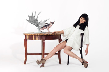 Girl Fashion model sits at a table on a white background