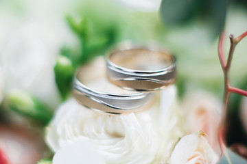 Wedding engagement rings and flowers wedding bouquet background, selective focus, macro