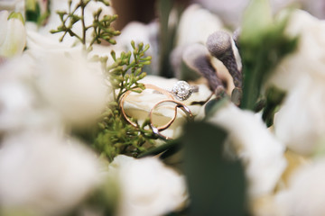 Wedding engagement rings and flowers wedding bouquet background, selective focus, macro