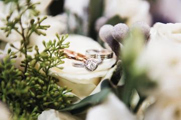 Wedding engagement rings and flowers wedding bouquet background, selective focus, macro