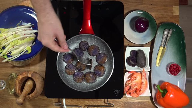 Top view food preparation Shrimp and violet potatoes to the pan on the stove with induction
