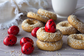 Traditional Greek Easter cookies with sesame seeds and colored eggs on the wooden table, selective focus, free space