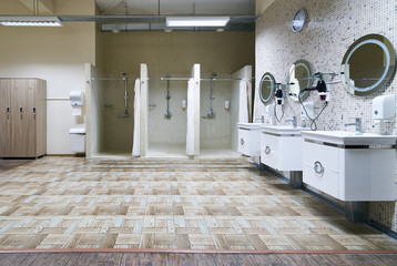 Public shower interior with everal showers, toilet sink and lockers in locker room in luxury fitness spa centre