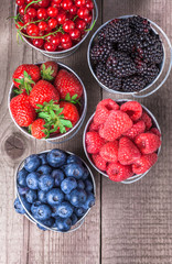 Berries closeup assortment overhead close up arrangement in five tin cans on wooden table in studio