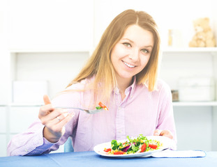 Obraz na płótnie Canvas Young smiling girl eating tasty green salad