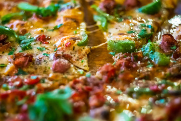 Italian fast food. Delicious  and appetizing hot pizza sliced and served on wooden platter with ingredients, close up view.