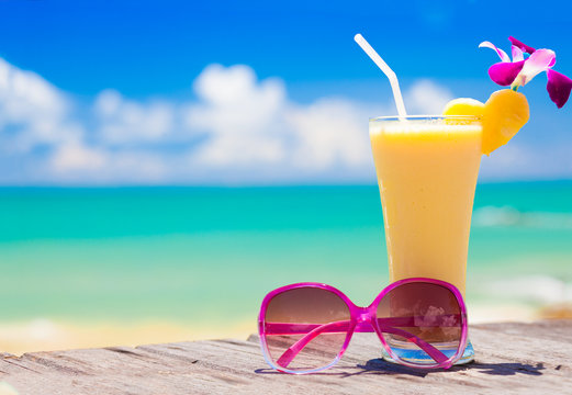 picture of fresh banana and pineapple juice and sunglasses on tropical beach