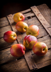 Peaches fresh arrangement on old rustic wooden box on bright light and dark background slanted in studio
